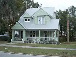 a green two story house with shingles