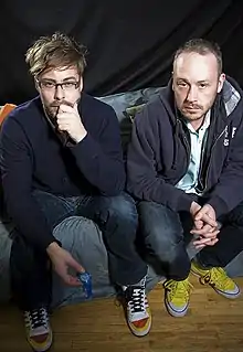 Colour photograph of Felix Buxton and Simon Ratcliffe of Basement Jaxx sitting on a sofa.