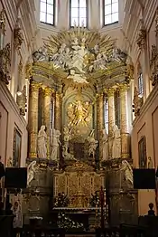 A gilded altar with six marvel columns and several sculptures in the background