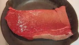 A beef round top round steak in a pan