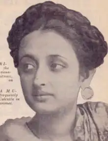 A young South Asian woman, her dark hair braided across the crown; she is wearing large round earrings