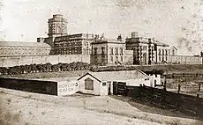 A line drawing of a large Victorian building in the background. In the foreground there is a representation of a small inn called the Bowling Green.