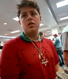 Benjamin Kapelushnik, wearing a red shirt and gold chain, authenticating a pair of sneakers in 2017