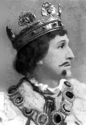 young white man with neat moustache and beard, wearing crown