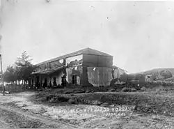 Black and white photo of a small brick house between fields of crops