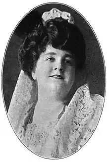 A white woman with dark hair and a round face, wearing a white lace mantilla.