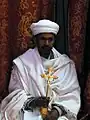 Ethiopian Orthodox priest holding golden blessing cross, Church of St. George, Lalibela, Ethiopia.