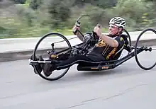 A recumbent racing handcycle with a streamlined frame and thin road racing wheels.
