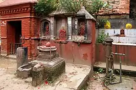 Some shrines in Bhaktapur with a disused jahru with two yellow spouts on the right. A well and a shelter are close by