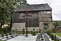 A cross with a house behind