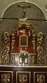 The icon in situ, with a red votive light under a carving of the Holy Ghost.