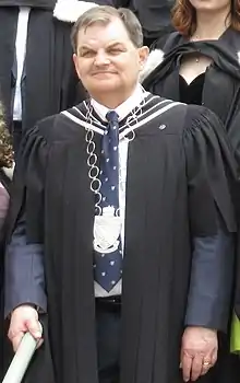 Waist-up photo of William Lahey, a white man in his early sixties with short brown hair, in his formal university regalia with president's medal and blue King's tie
