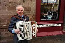 Wilkie playing his accordion outside his shop in Perth city centre