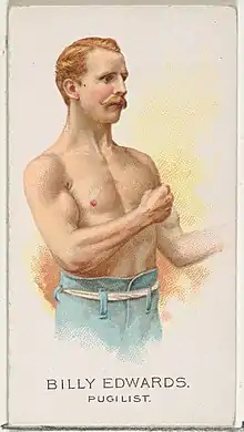 Bare chested man from waist up with raised fists in boxing stance.