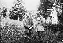 Black and white photo of two men standing in front of trees