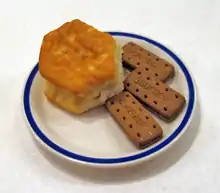 One baking powder biscuit and three darker cookies on a plate