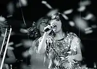 A woman singing into microphones