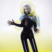 A white and yellow color mixing on the background and Björk is standing in the middle wearing a ring and a fit latex dress that covers her hairline and on the hairline and arms she is wearing porcupine looking spikes