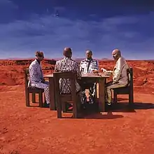 Four men sitting in a table at Bardenas Reales with horses on the table and the earth and moon in the background