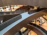 Spiral bronze coloured ramps connecting floors in an office building, viewed from above