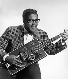 Publicity portrait of American blues musician Bo Diddley, 1957, sitting with his "Twang Machine", a unique square electric guitar built for him by Gretsch.