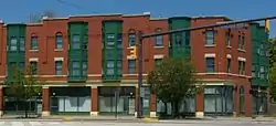 A block of red and green painted three-story apartment buildings