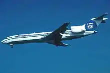 Left side view of an aircraft approaching an airport, with its nose pitched down slightly: In the background is blue sky.