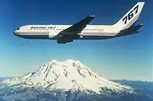 Boeing twin-engine jetliner in flight near a snow-capped mountain