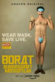 Baron Cohen as Borat in a speedo in the style of a surgical mask, smiling and giving thumbs up. Text surrounding him says "WEAR MASK. / SAVE LIVE.".