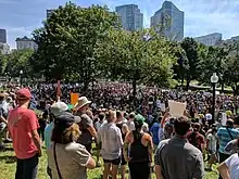 A large group of people stand outdoors in the Boston Common