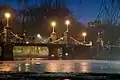 Boston Public Garden Foot Bridge at night, 2007. The bridge is illuminated by lampposts, and several people are standing on it.