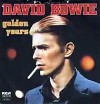 A close-up of a younger man with slicked back red hair holding a cigarette in his mouth looking to the left. "DAVID BOWIE" appears above hi m in big red letters with "golden years" in all lowercase to his left