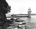Historic view of Bradleys Head Lighthouse showing the Sydney Harbour Trust workboat Aurora in the background. Note the different light source and the bell