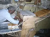 A worker using a bread slicing machine to slice loaves of bread