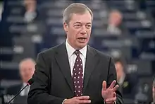 A man wearing a suit, standing at a podium