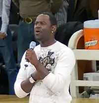 Brian McKnight, wearing a white sweatshirt and singing into a microphone at a stadium