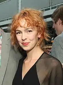 A woman with red hair, wearing a black outfit.