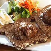 Broodje bal, a slice of bread with a meatball and gravy, halved meatball served on slices of Dutch whole wheat bread.