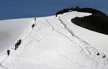 Tourists hiking up and sledding down the hill above the base