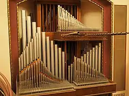 A large Schantz pipe organ with exposed pipework and no case. There are platforms for the great, positive, and swell divisions, with a large swell box in the center.