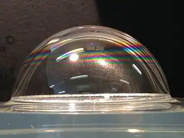 A soap bubble wetting a liquid surface