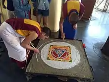 Buddhist Monks performing traditional Sand mandala made from coloured sand