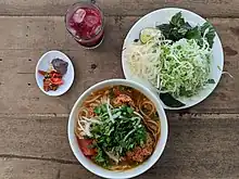 A bowl of bún riêu, served with fresh herbs and nước mắm