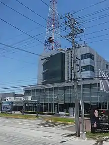 Corporate Guarantee and Insurance Company building, the headquarters of CLTV 36, a four-story modernist office building with a tall red and white antenna behind a BMW dealership, on Jose Abad Santos Avenue in San Fernando, Pampanga, April 2017
