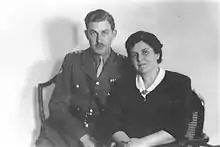 A man in military uniform seated next to an older woman.