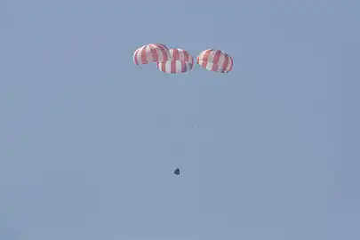 Dragon descending under parachutes