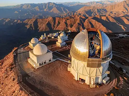 the Víctor M. Blanco 4-meter telescope on the summit of Mt. Cerro Tololo (foreground) with many other NOIRLab-operated telescopes
