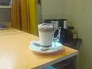 A caffè mocha sitting on a white plate and beige table.
