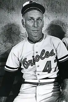 A man in a light baseball jersey and dark cap