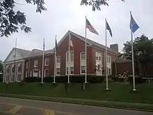 View of the front brick exterior entrance of the museum with six flag poles set slightly up a hill from the 2nd street road surface.